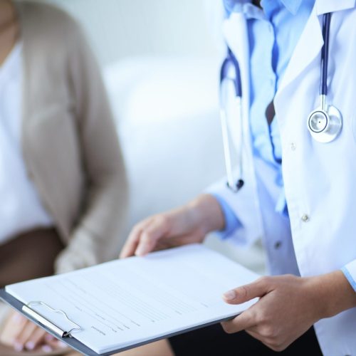 Female doctor holding application form while consulting patient